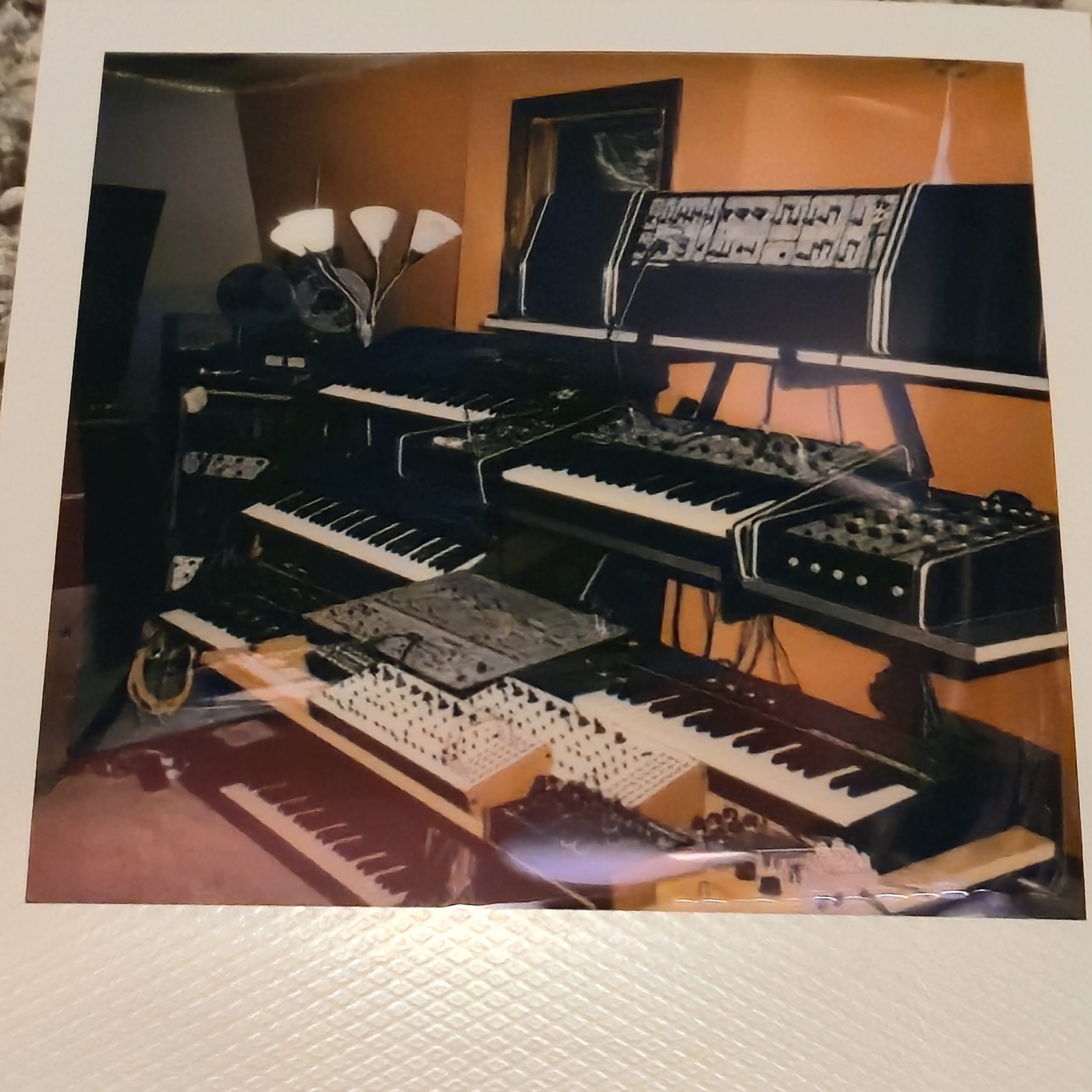 Polaroid photo of a synth studio with keyboards and a synthesizer.